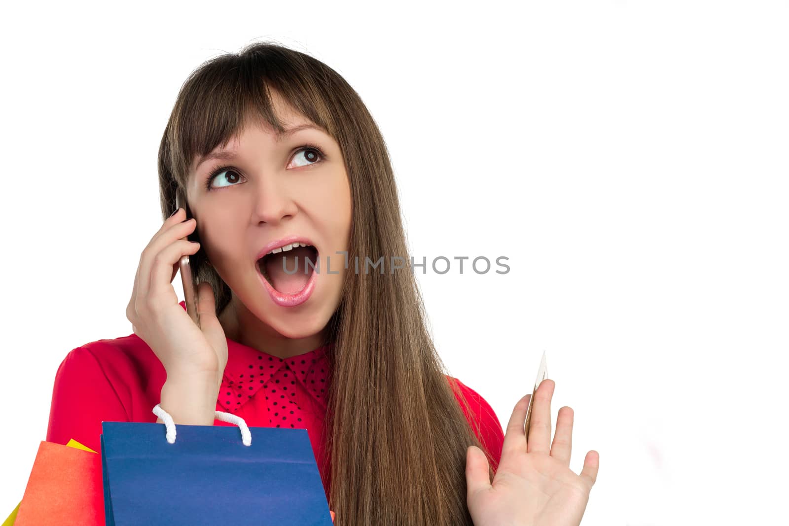 Young woman shopping with credit card holding colourful paper bags and packages talking on smartphone