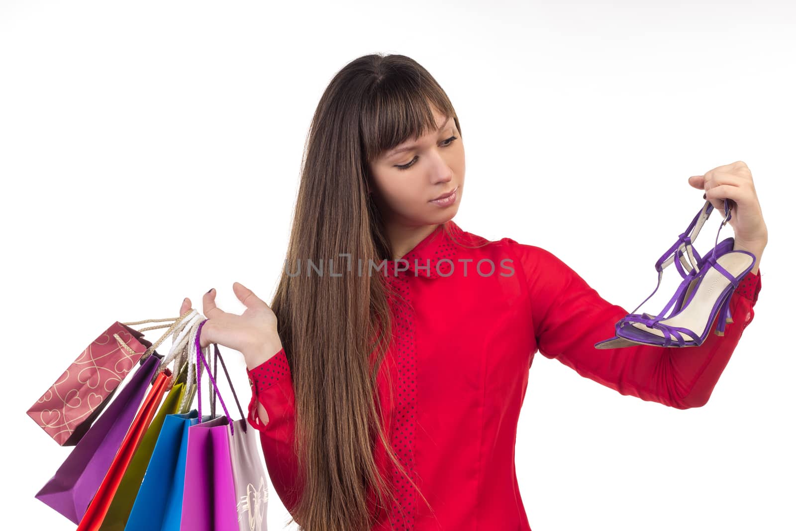 Young long-haired woman holds her purchases, many colorful paper bags, packages, and shoes in her hands after shopping