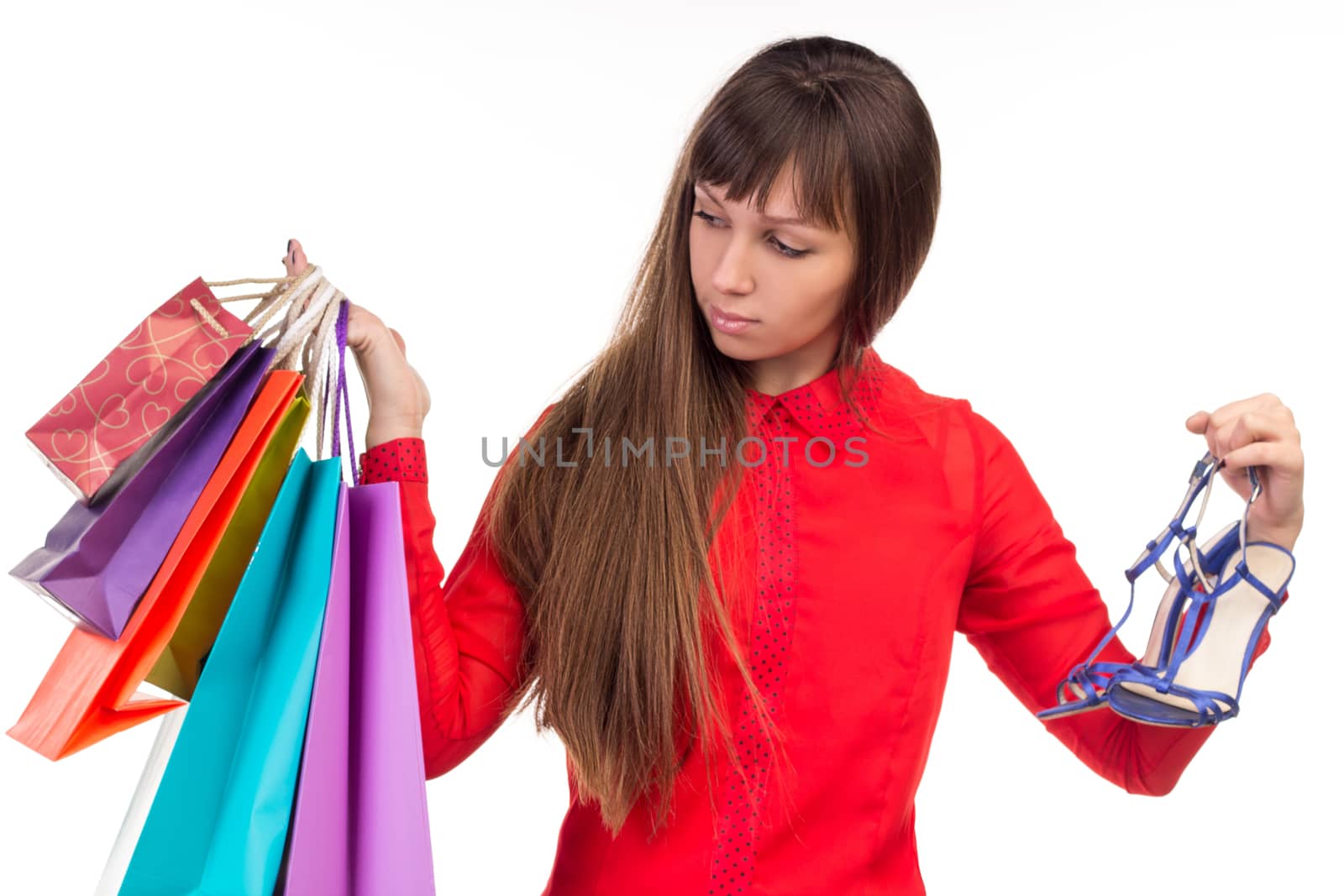 Young long-haired woman holds her purchases, many colorful paper bags, packages, and shoes in her hands after shopping