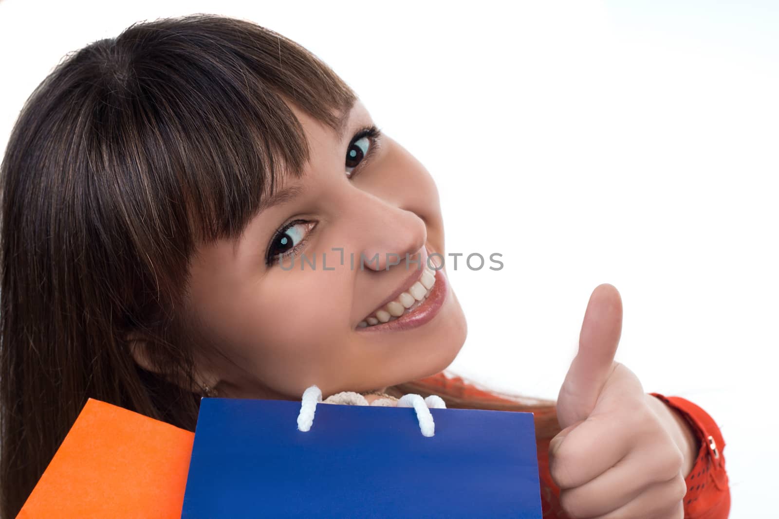 Smiling young woman at shopping with colourful bags shows a good sign with her finger