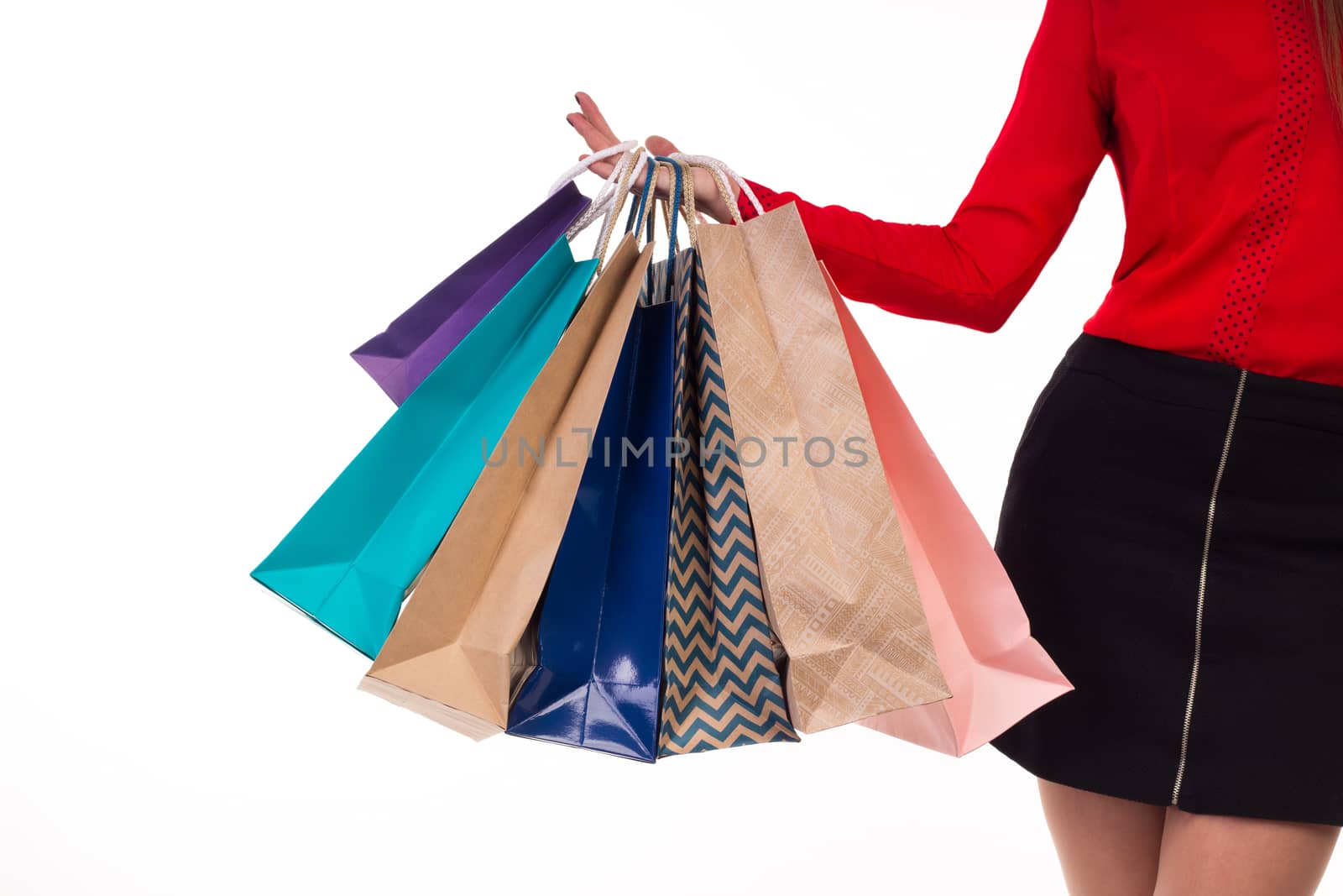 Colourful and bright shopping paper packages hanging on female right hand