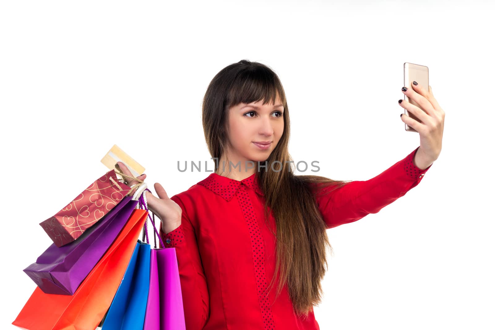 Young woman shopping with credit card holding colourful paper bags and packages does selfie