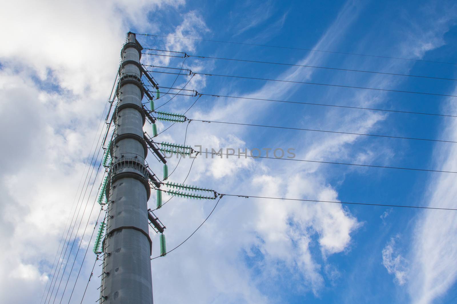 High-voltage power lines and insulators over blue sky background