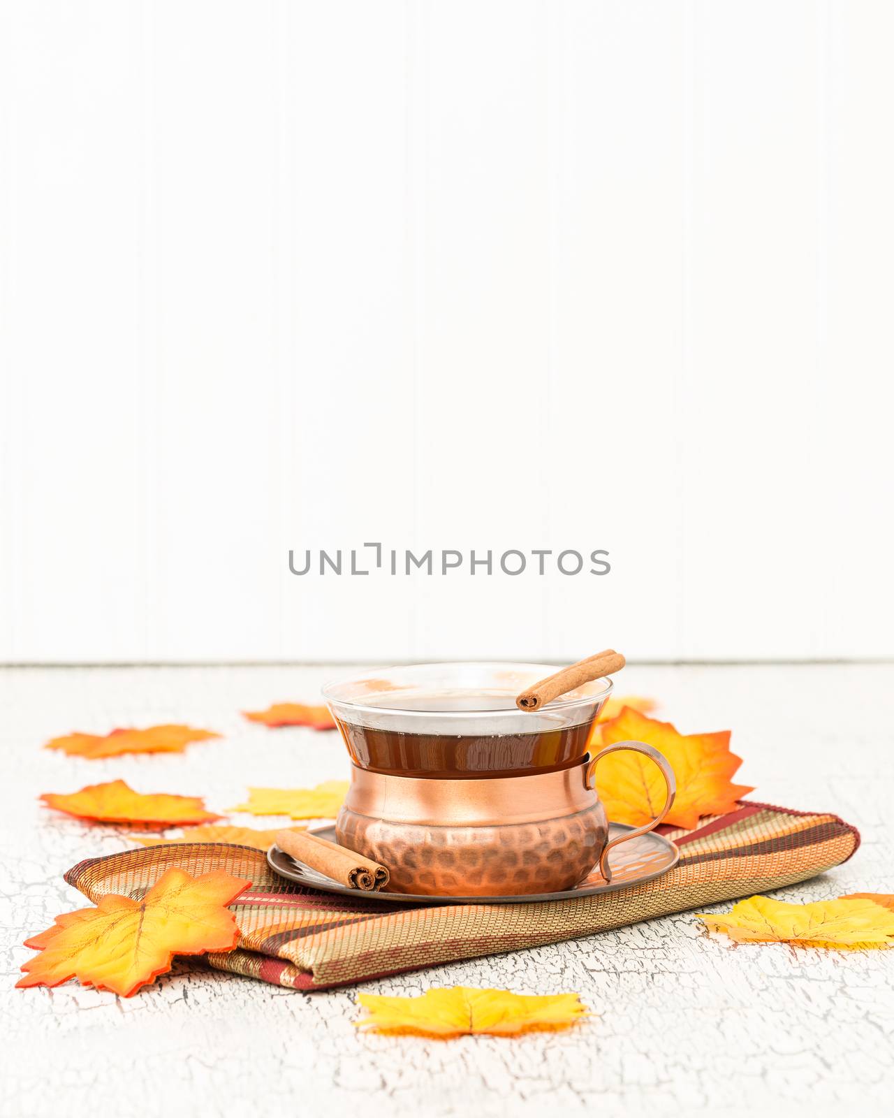 Cup of hot chai tea with colorful autumn leaves.