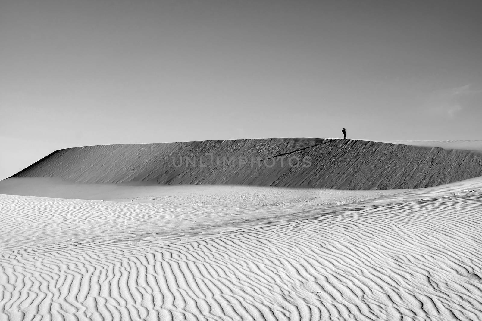 Life is the trip, lonely man enjoy calm scene on Vietnamese sand hill, sandhill with amazing shape in black and white tone in summertime, adventure travel in the choice of freedom young people