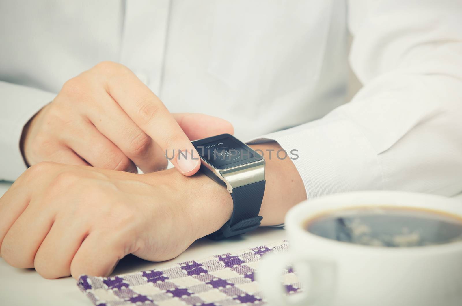 Businessman working with smart watch in restaurant. Coffee on the table 