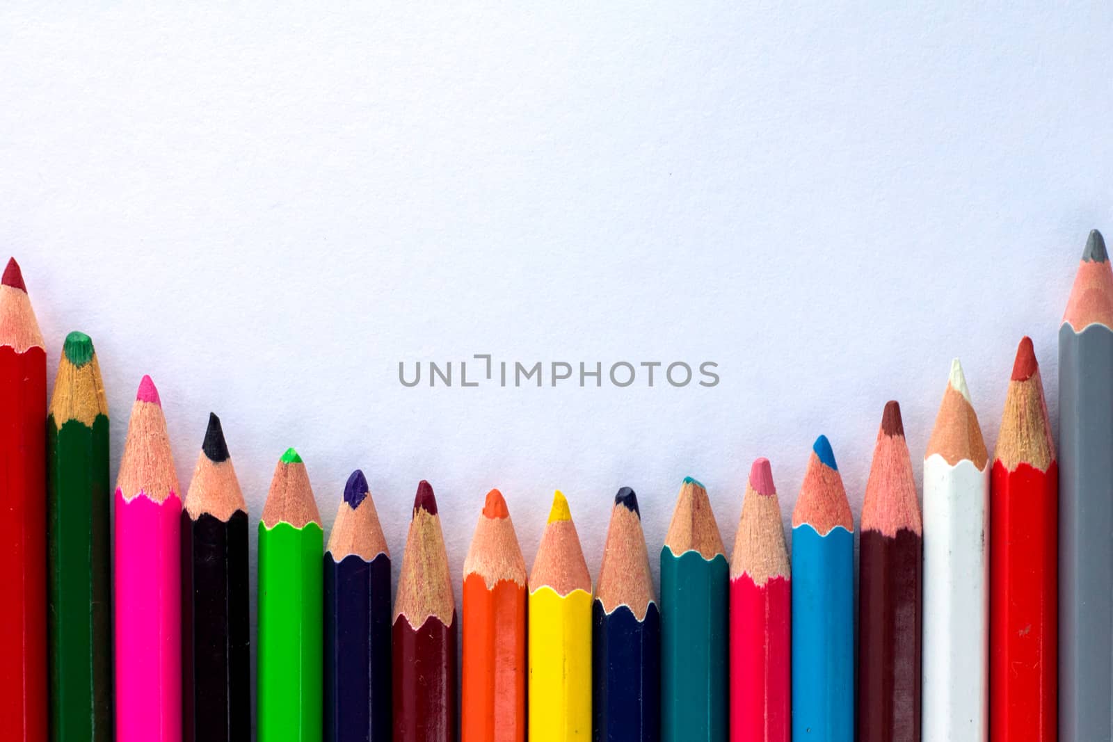 White background for presentation with round horizontal colourful bottom border of multicoloured wooden pencils