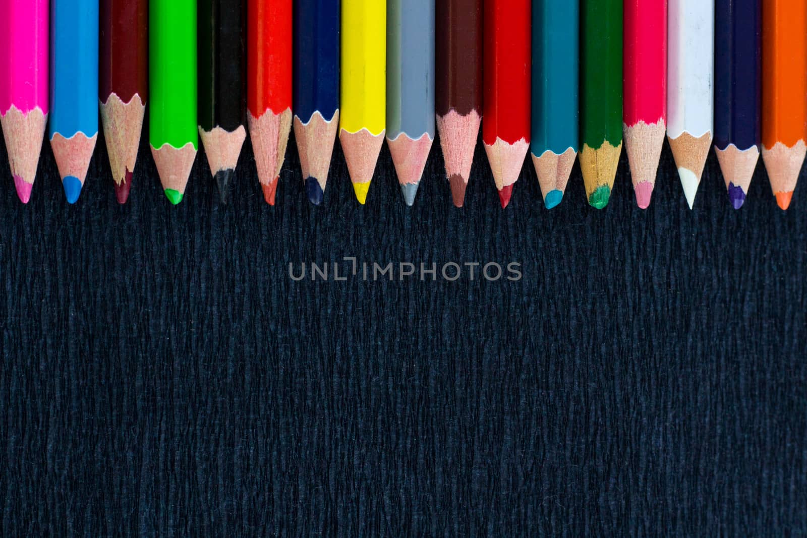Black background for presentation with horizontal colourful upper border of multicoloured wooden pencils