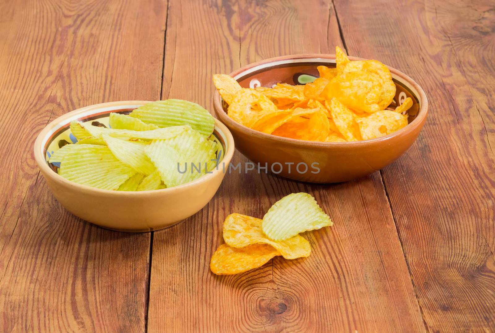 Potato chip flavored wasabi and paprika in two different ceramic bowls on an old wooden surface
