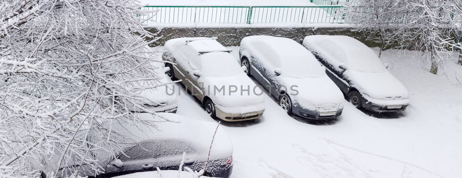 Cars covered with snow on parking lot in residential area by anmbph