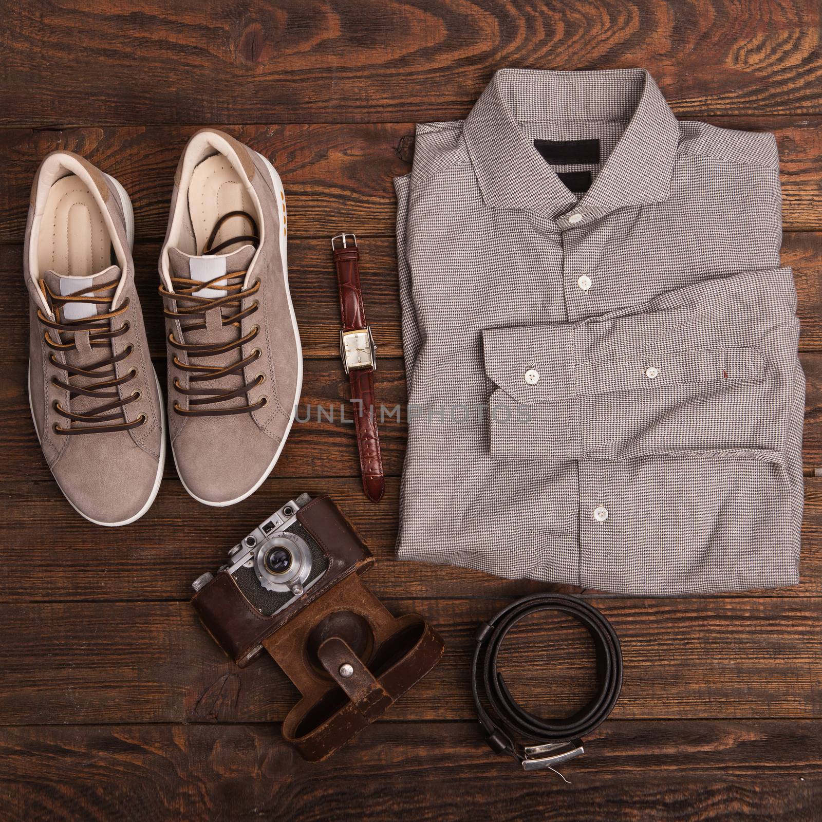 Flat lay of modern men's clothing on a brown wooden background. Top view of hipster clothes and accessories