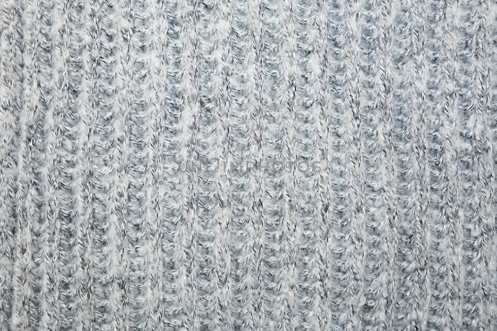 Close up on knit woolen fur texture. Gray melange fluffy woven thread sweater or scarf as a background.