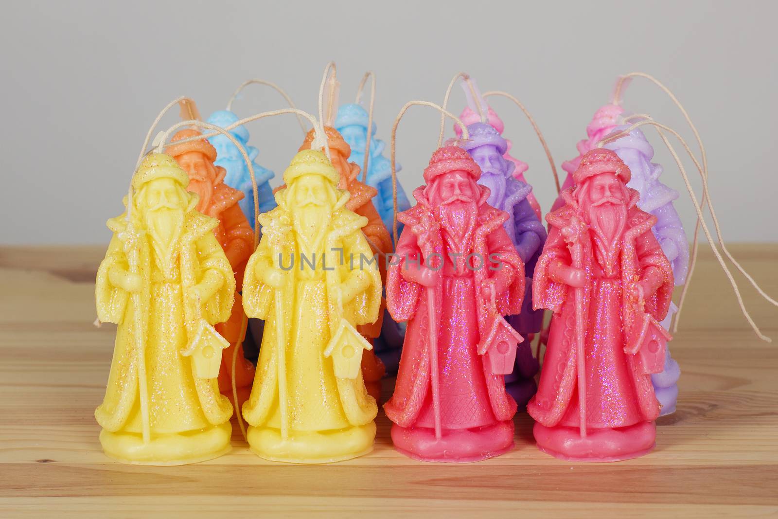 Colorful handmade Souvenir Christmas candles in the shape of Santa Claus on a wooden textural background