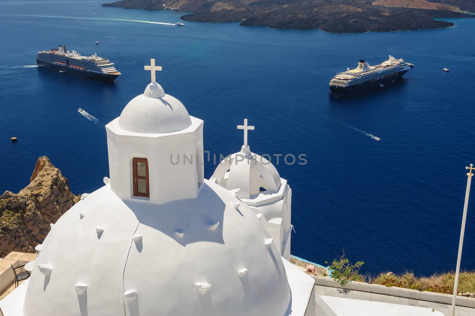 White orthodox church bell tower and sea with ships at background. Fira, Santorini Greece. Copyspace