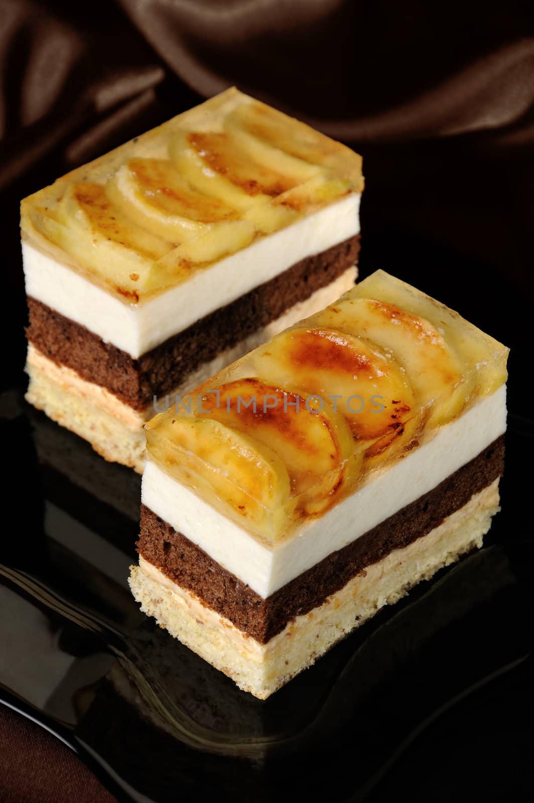Cake stacked from caramel, apple mousse, chocolate and almond biscuit with a jelly layer of slices caramelized apple