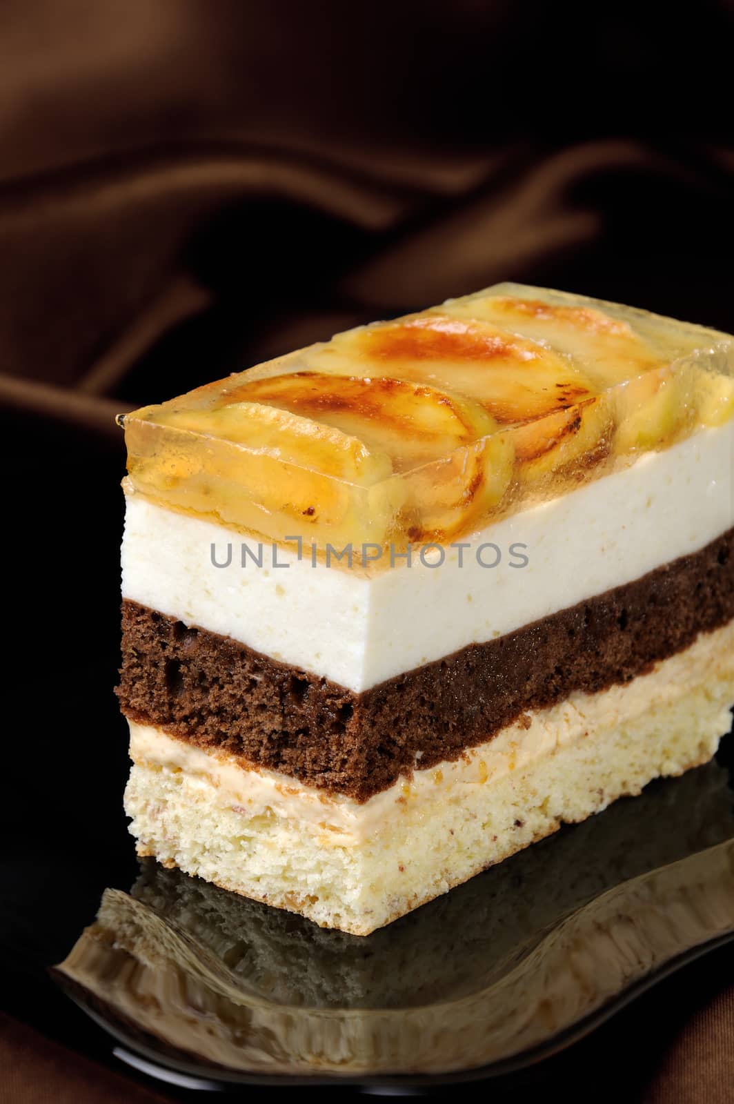 Cake stacked from caramel, apple mousse, chocolate and almond biscuit with a jelly layer of slices caramelized apple