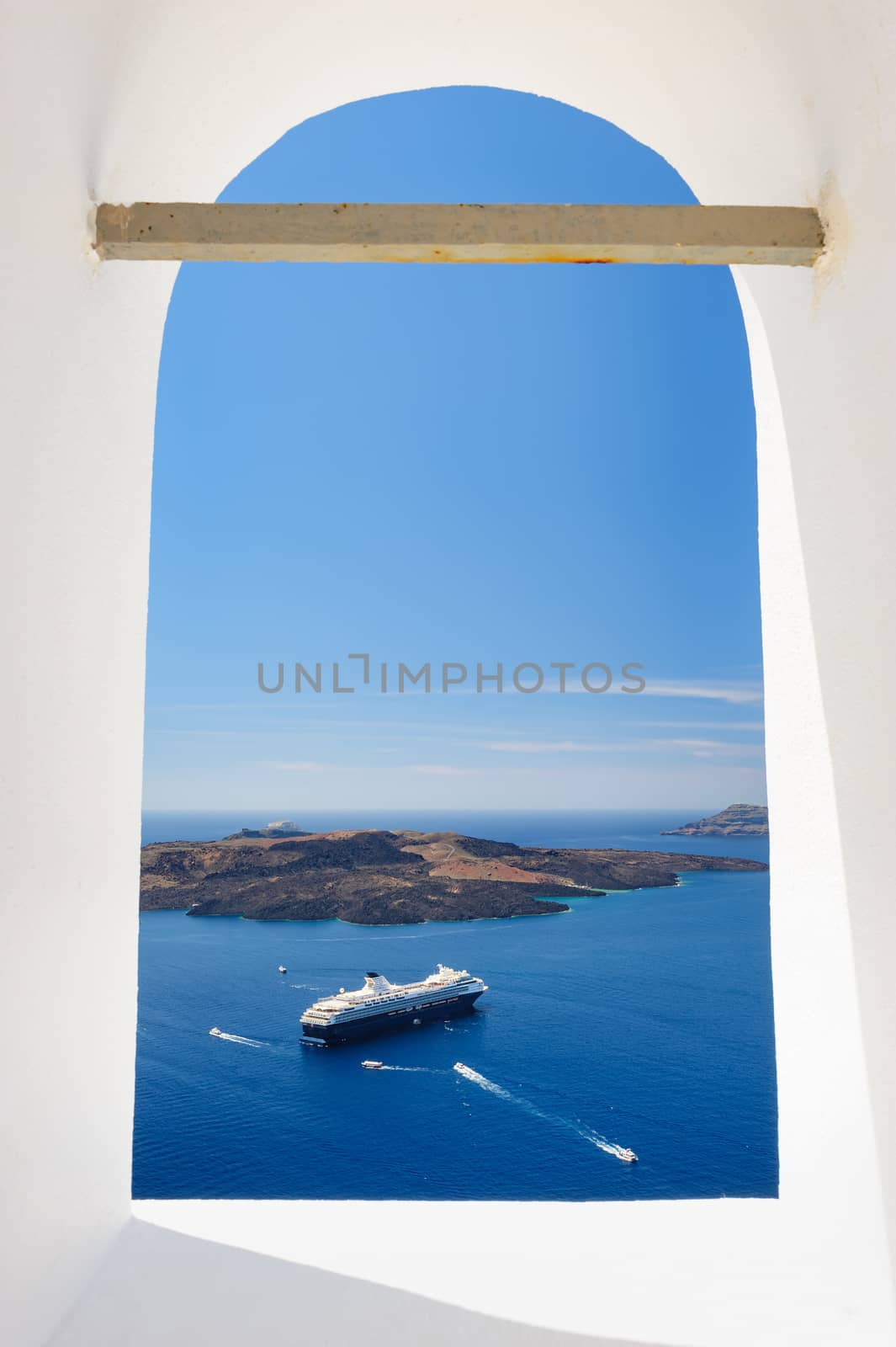 View from church's window in Fira town to the caldera sea with ships and volcano island. Santorini, Greece. Copyspace.