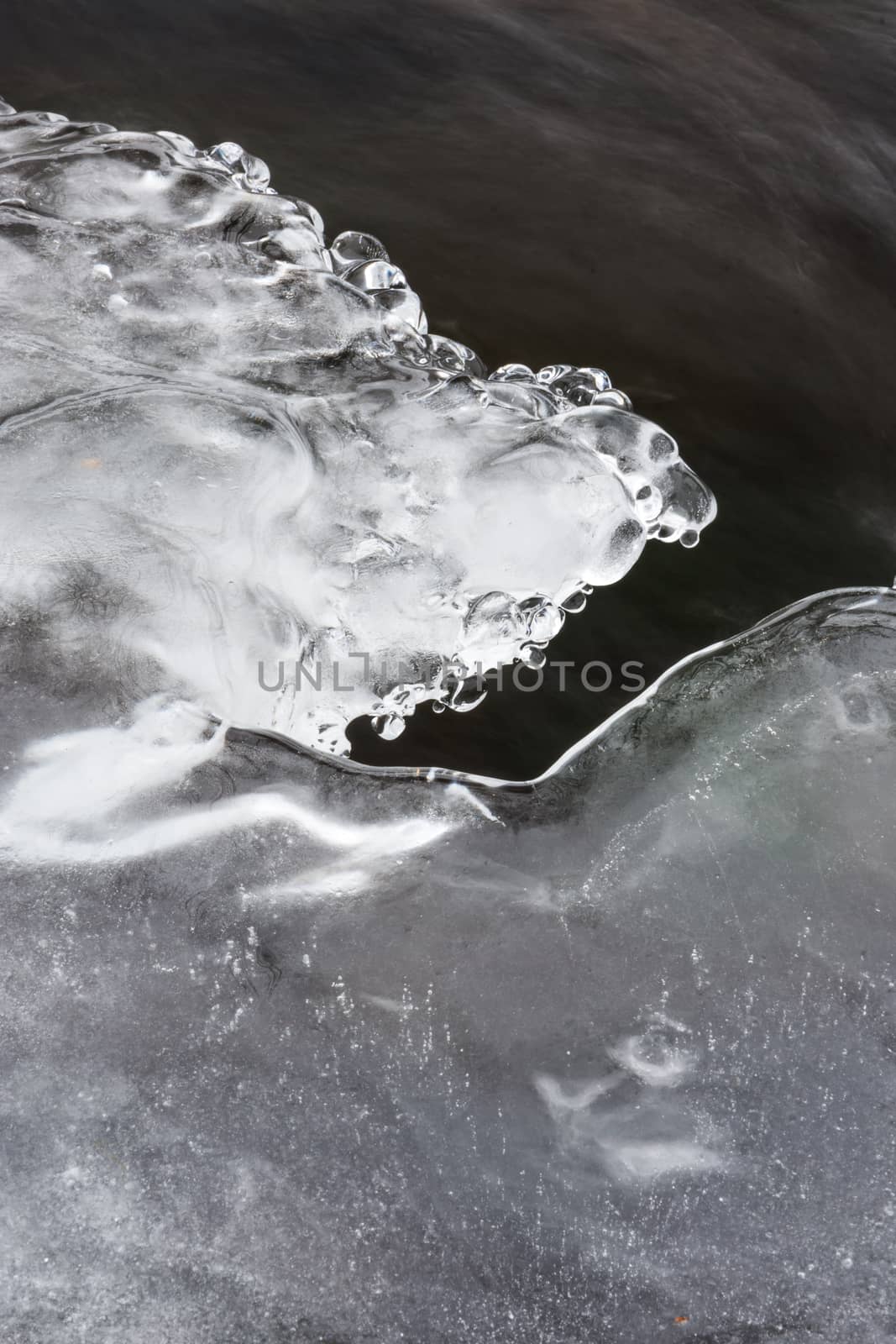 Icy ornaments on a small stream, black water