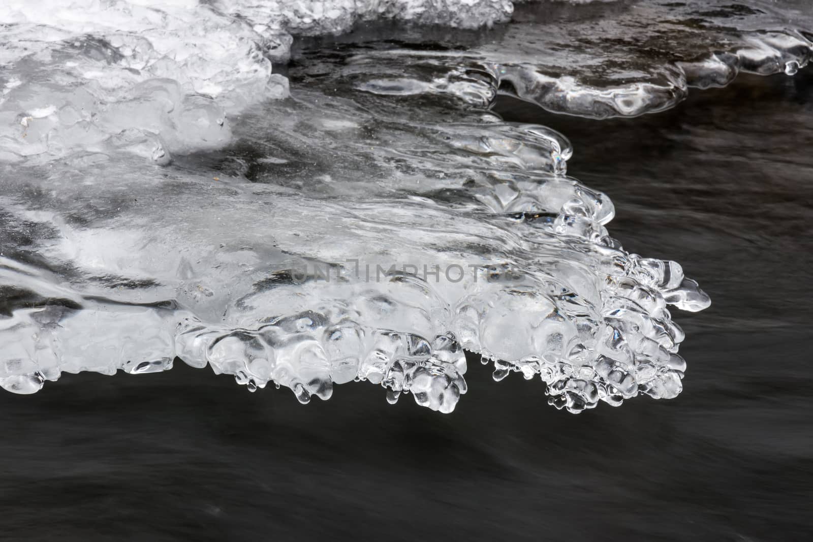 Icy ornaments on a small stream, black water