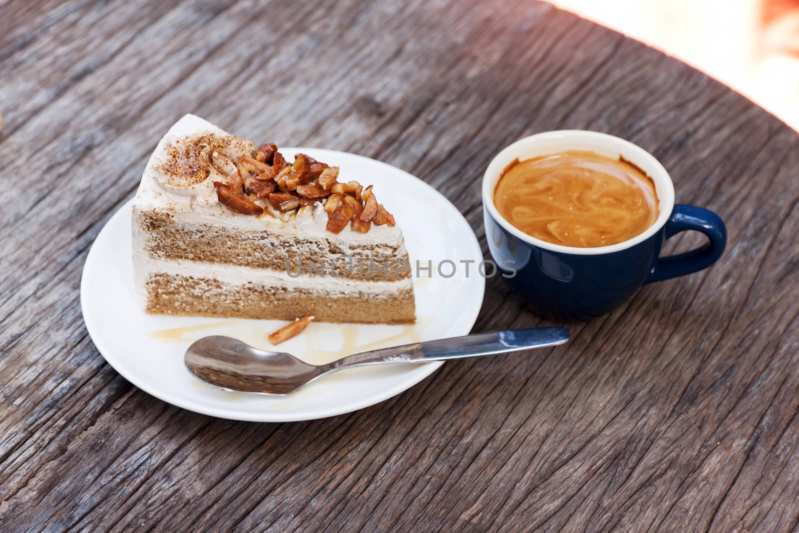 Coffee cake with topping almond on white plate  and hot espresso on old wood table