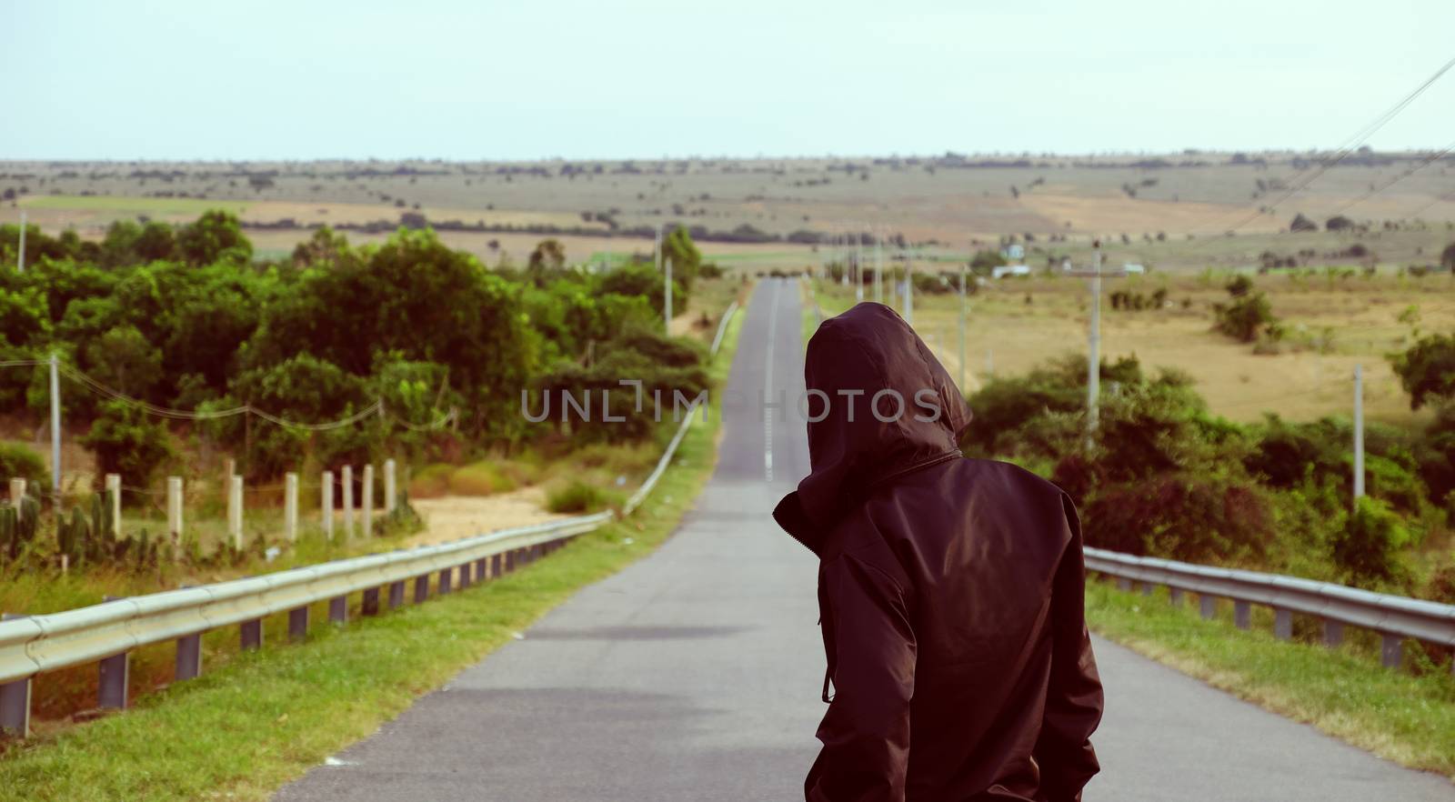 Asian man stand on the way and look forward to face with his choice, straight highway ahead at Vietnam countryside, male wear black jacket  to illustrate for attitude to make life successful