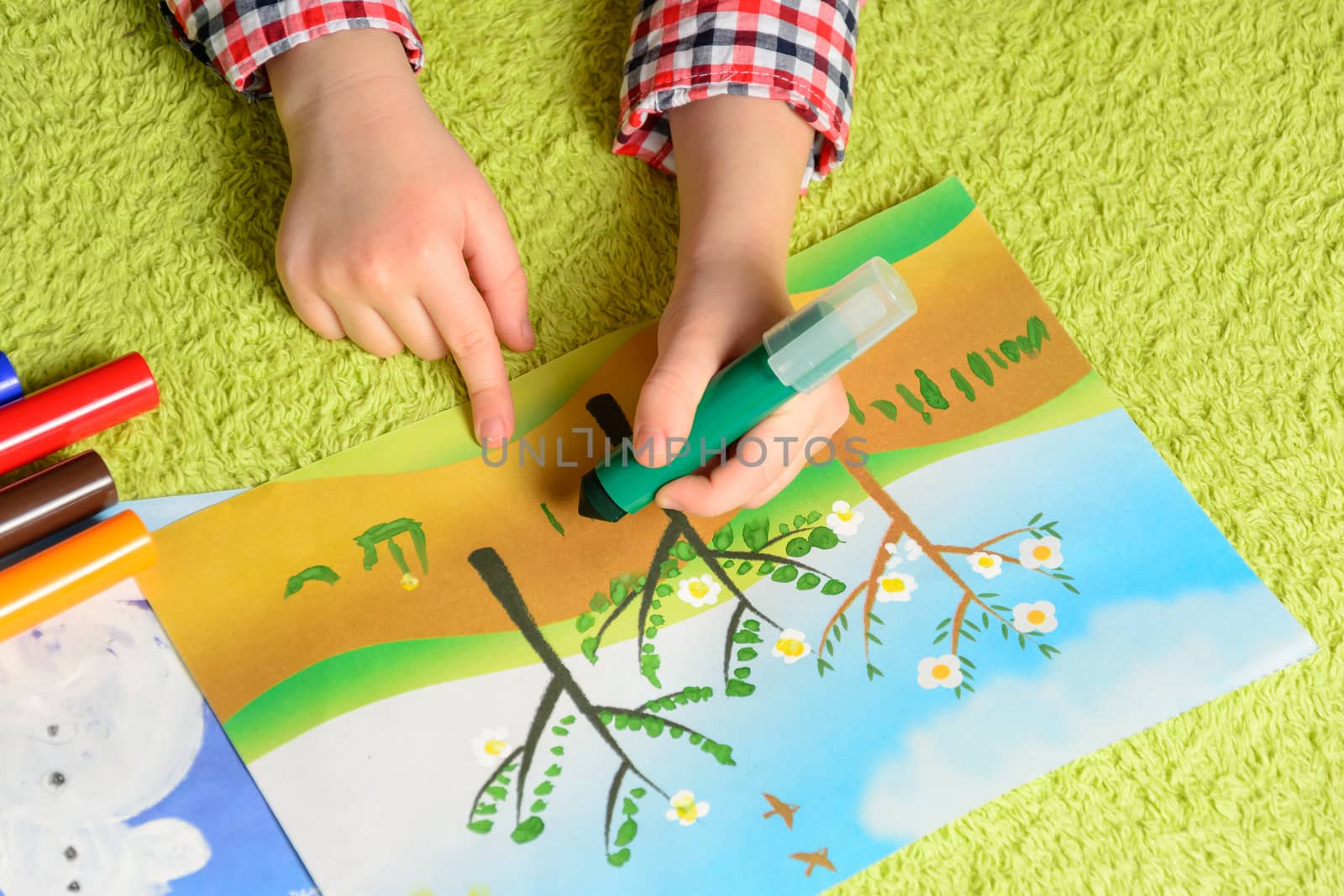 the child draws a picture lying on a green carpet