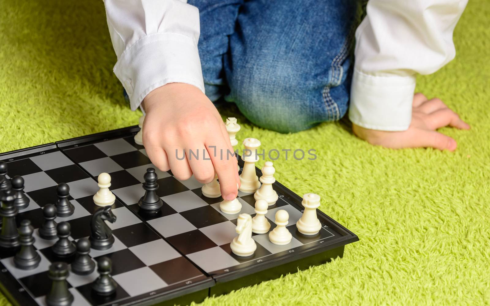 child playing chess sitting on the carpet