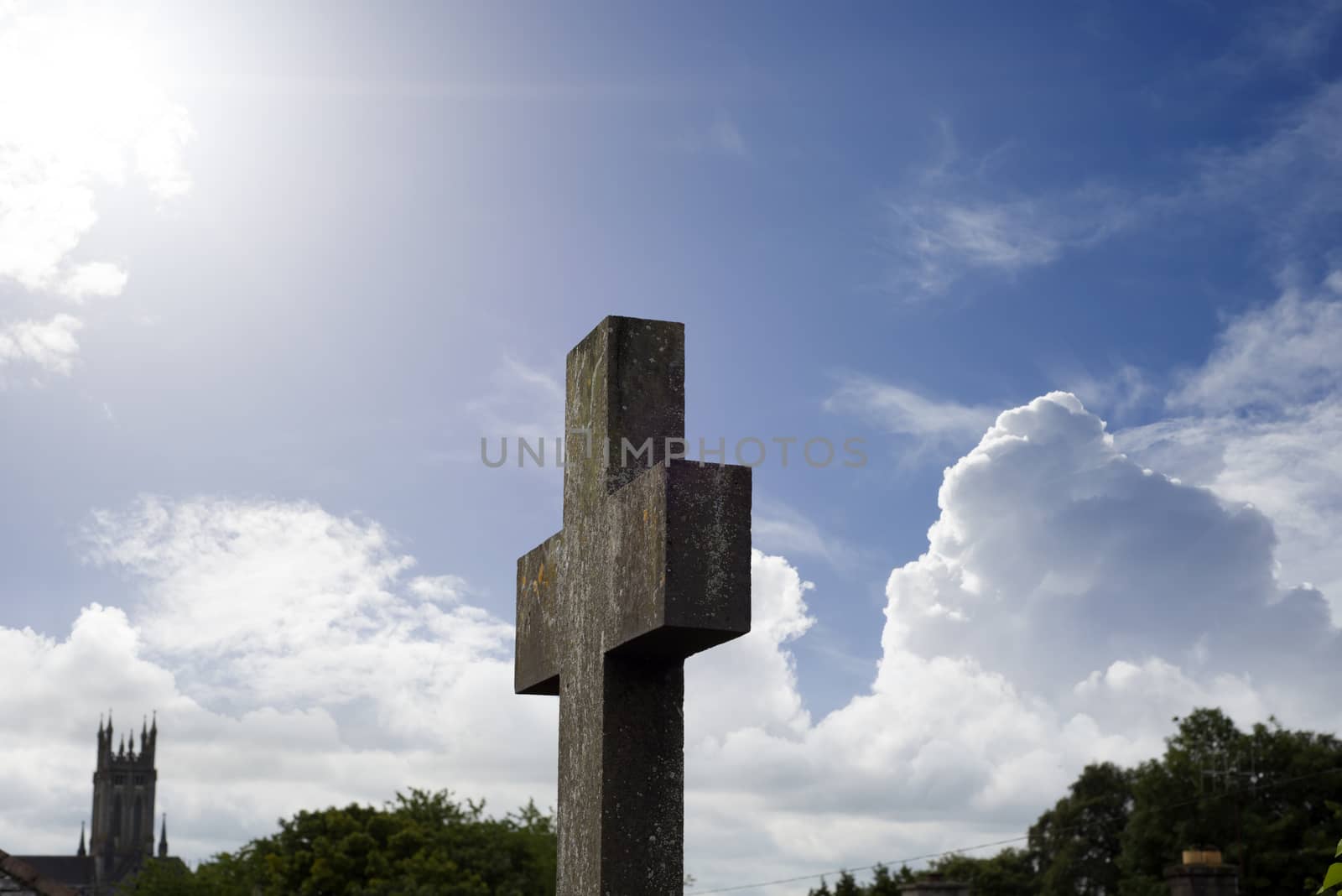 sun rays over cross at ancient graveyard by morrbyte