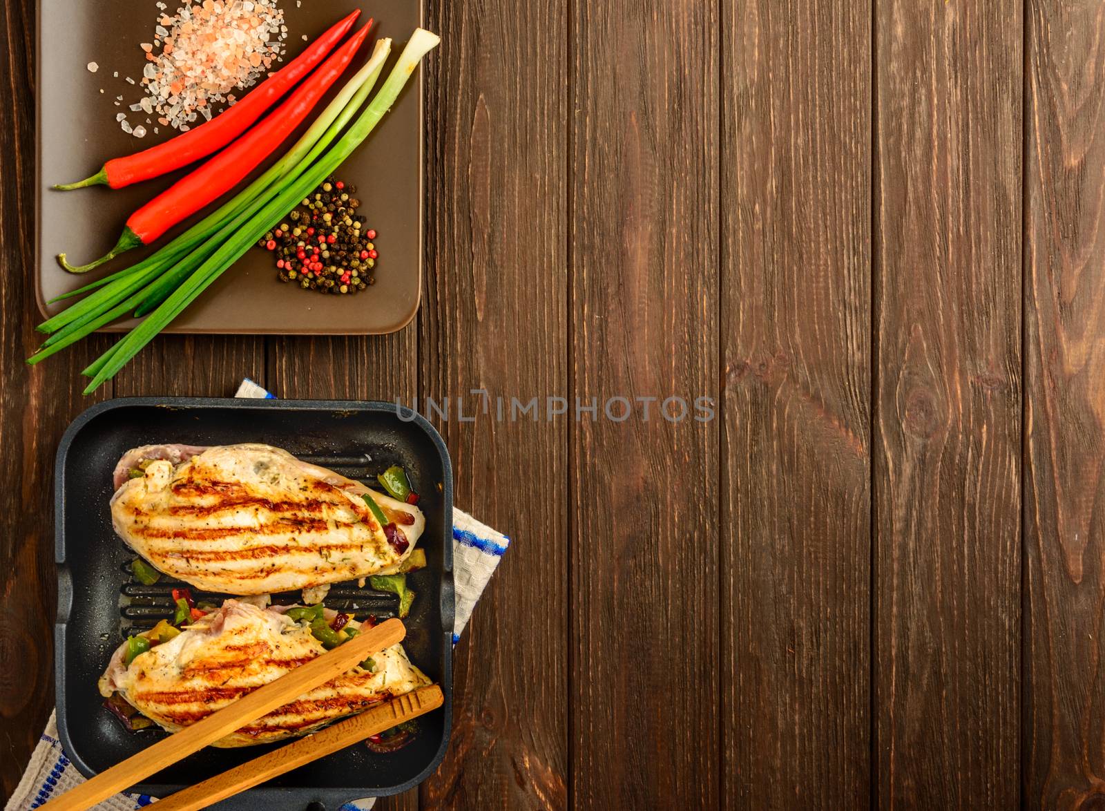 The juicy chicken fillet and vegetables made on a grill on a brown wooden background. Flat lay, copy space.