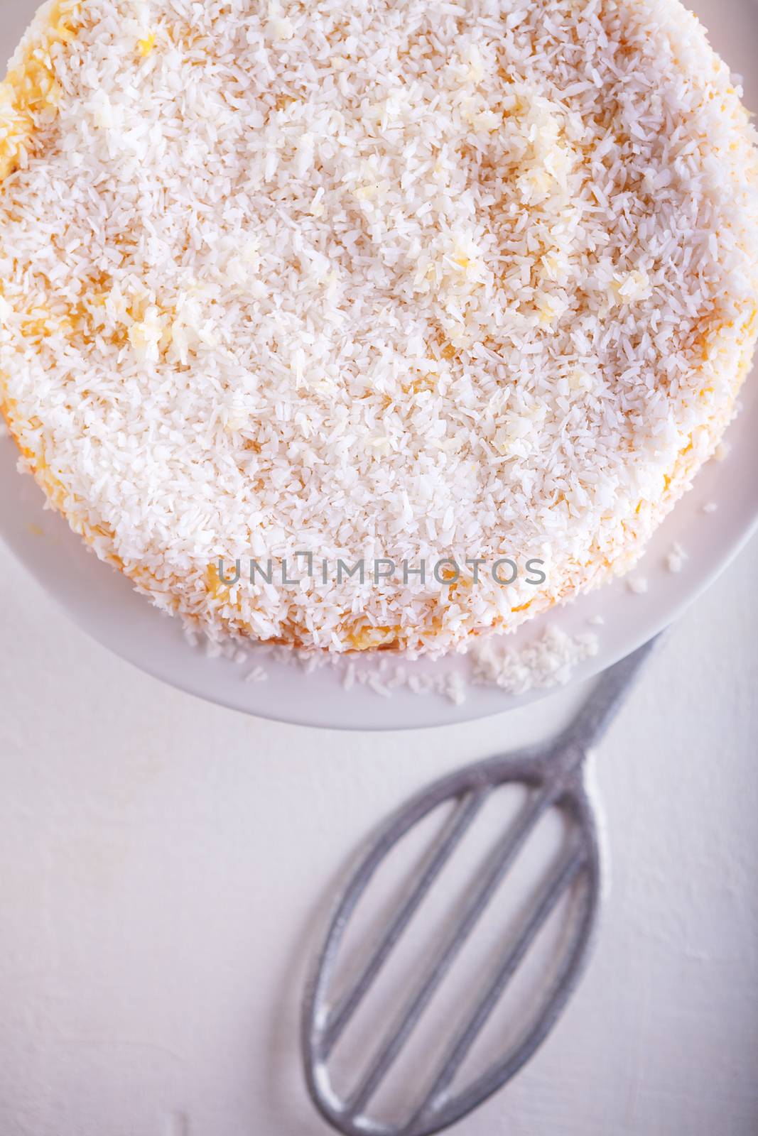 A piece of Homemade coconut cake on a white plate.