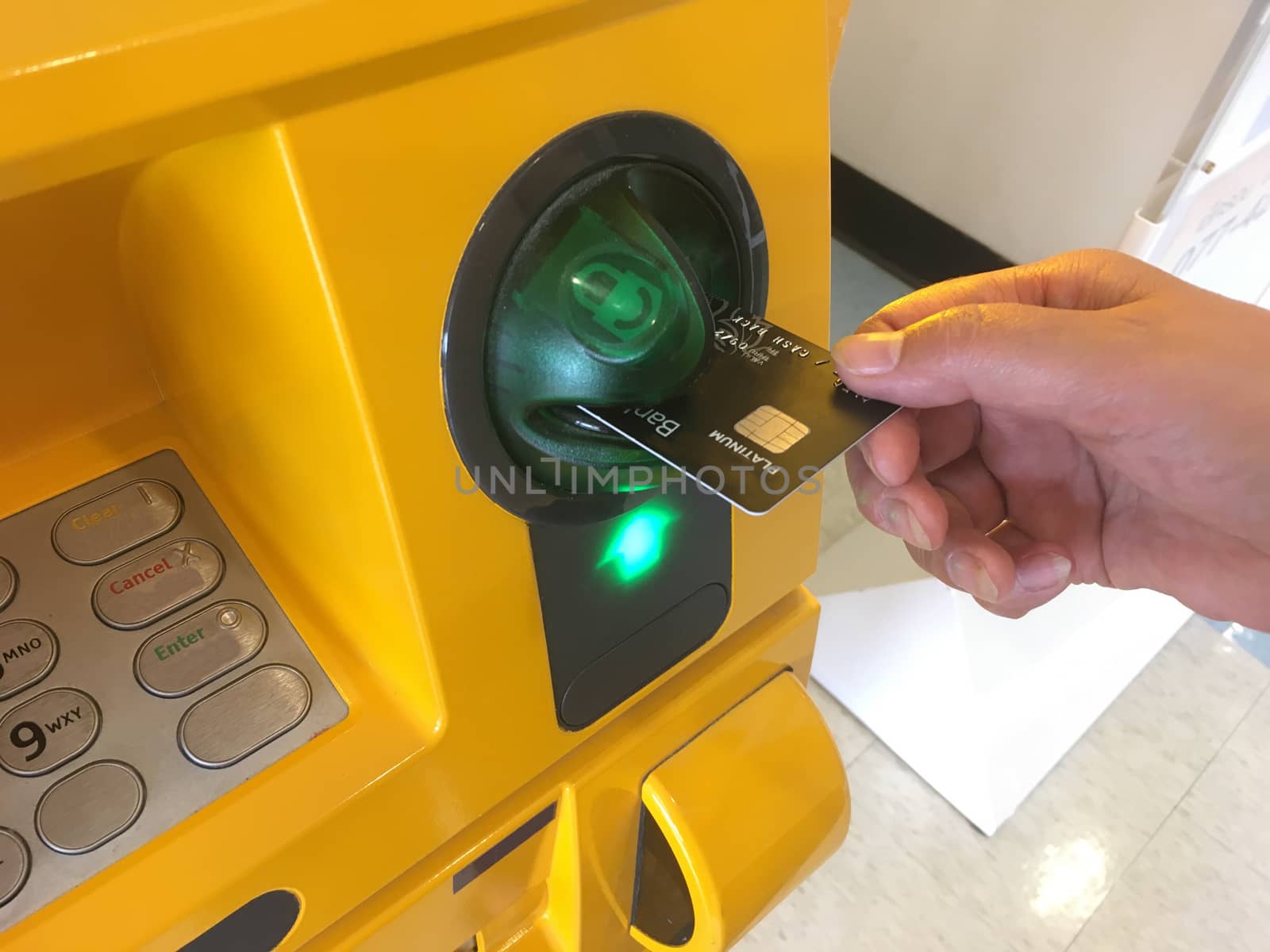 Closeup of hand inserting ATM card in bank machine for withdrawing money.
