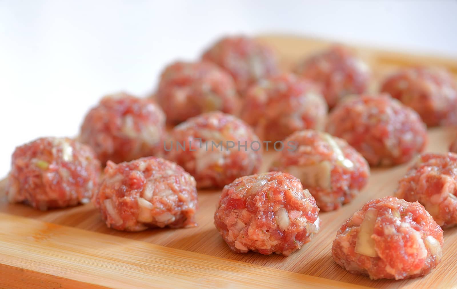 Raw Uncooked Meatballs on wooden plate