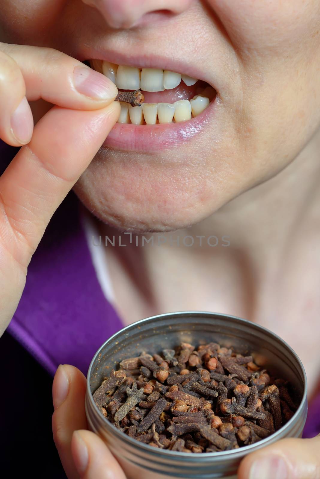 Woman chew dried clove spice by jordachelr