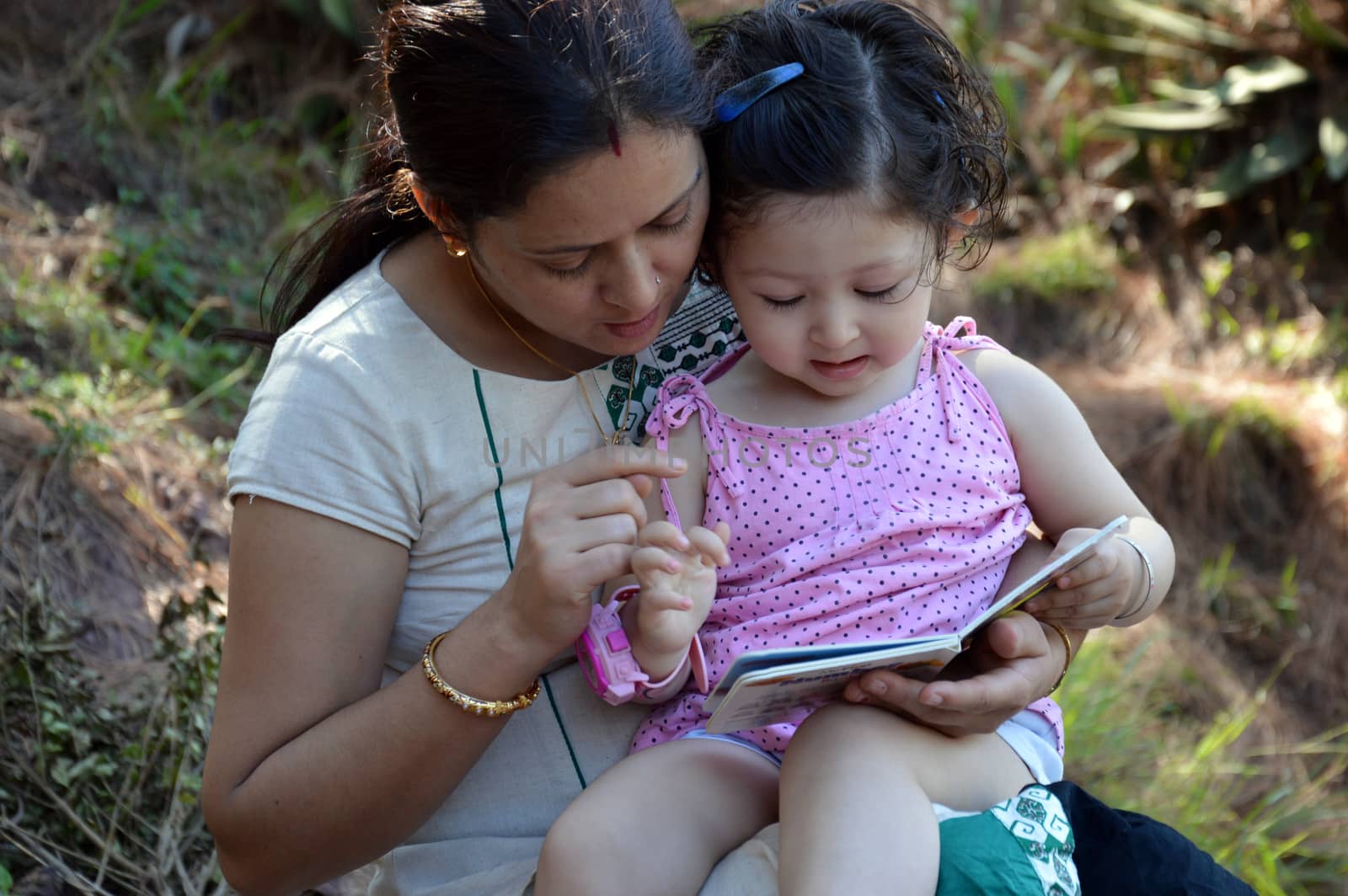 Mother reading book with her two year's old child.