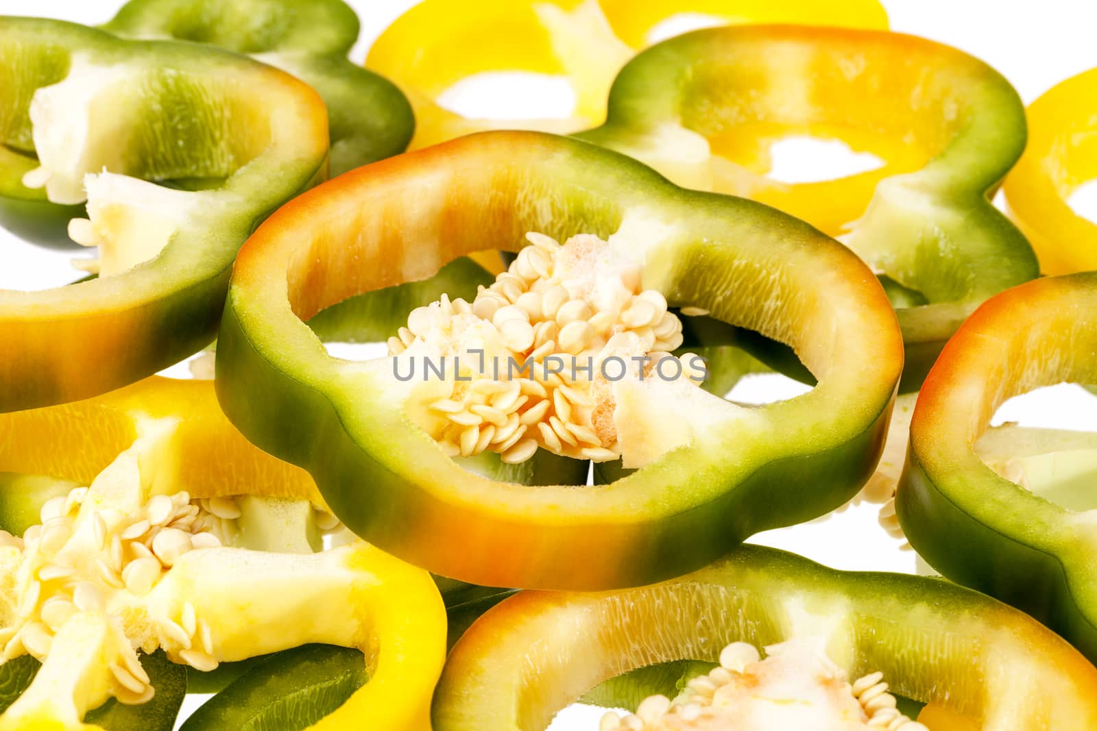 Slices of yellow and green pepper vegetables on white background.