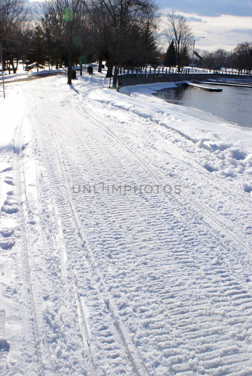 A closeup vertical view of some fresh snowmobile tracks in the winter snow.