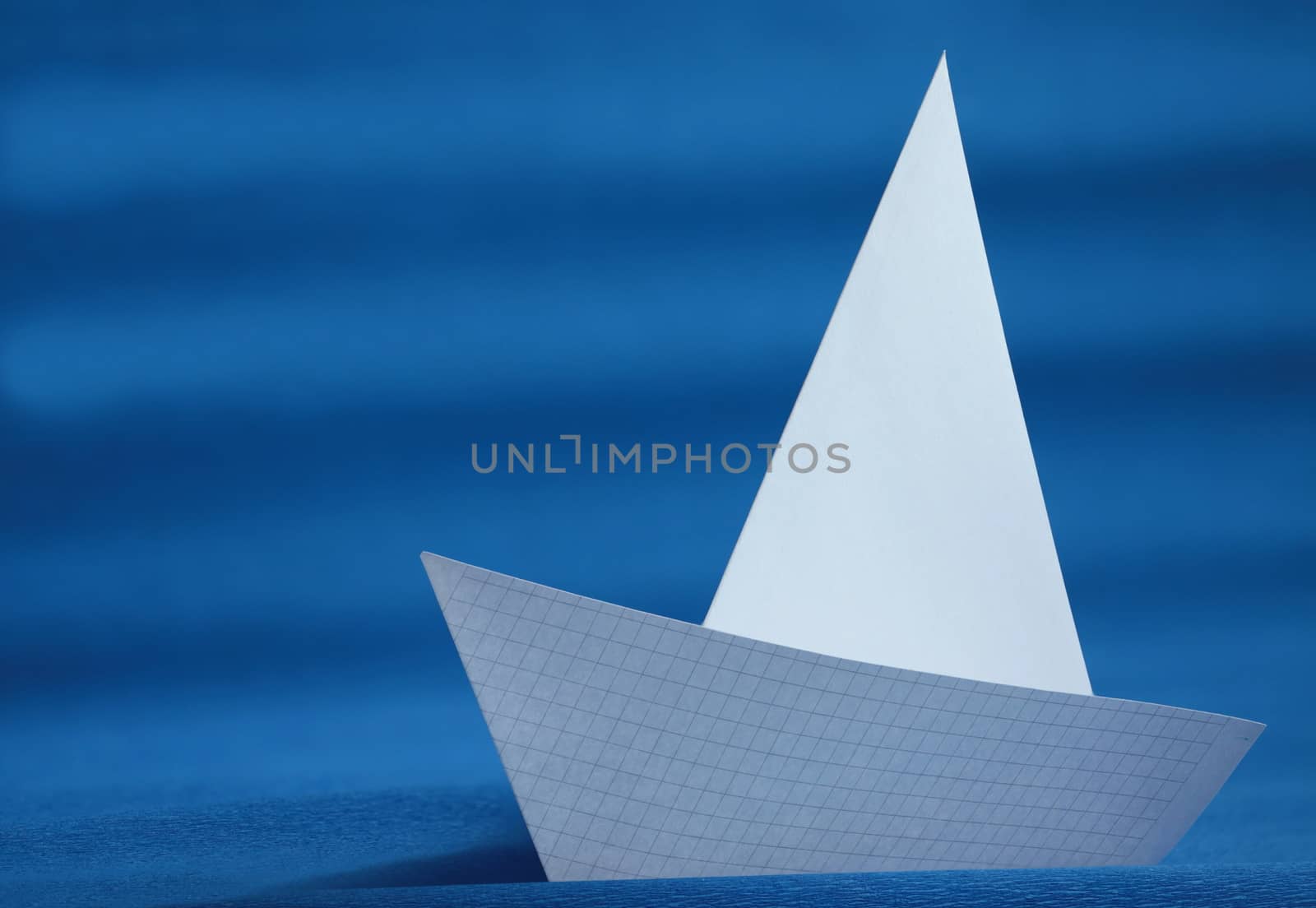 origami white paper yacht on blue sea 