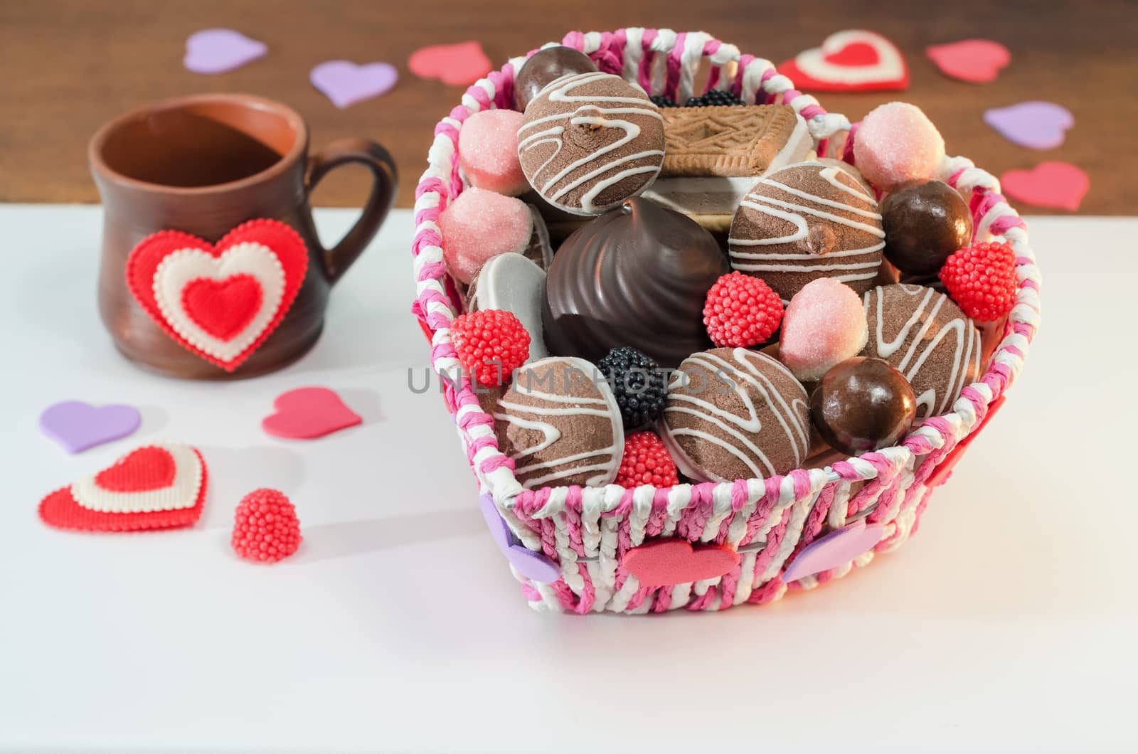 Basket with various sweets and biscuits on the table, decorative Valentine day heart. Selective focus.