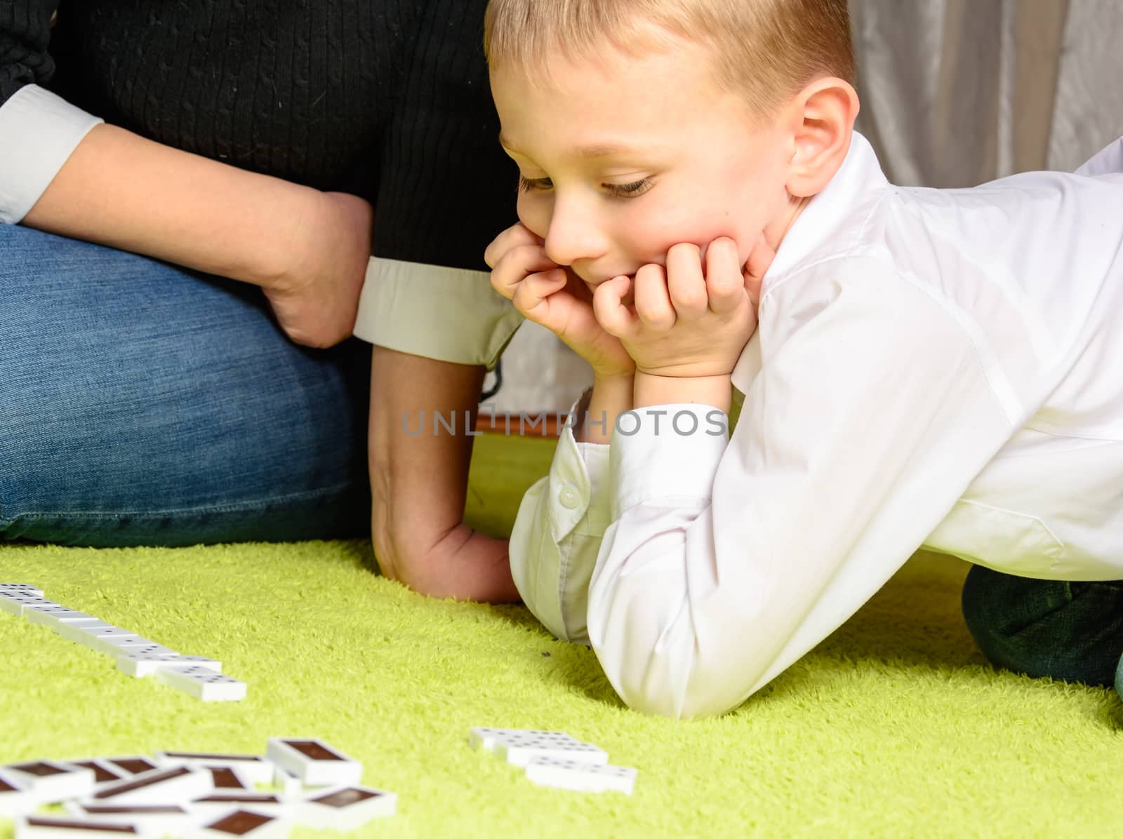 child with his mother playing dominoes lying on the carpet