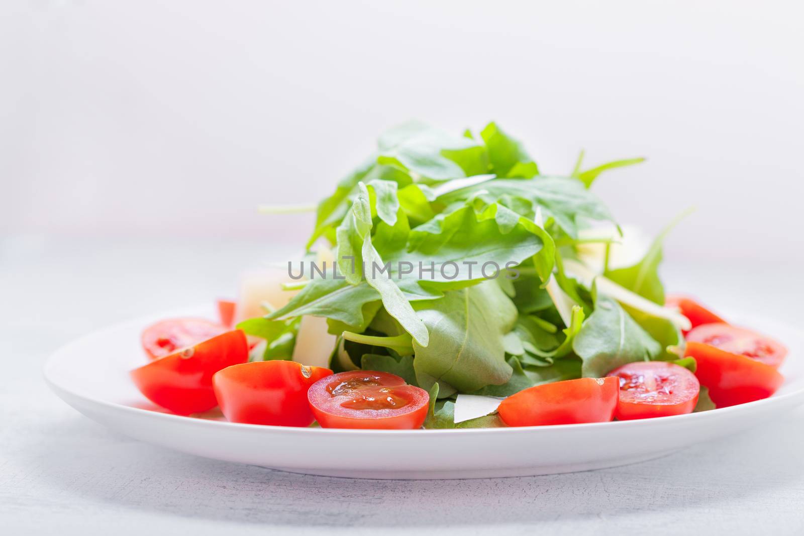 Salad with arugula, tomatoes on a white background