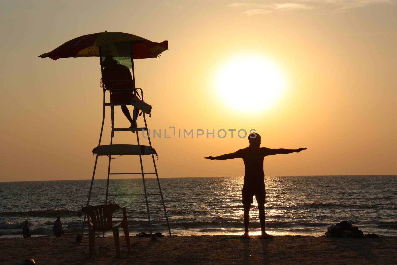 The man is engaged in sports at sunset near the lifeguard tower