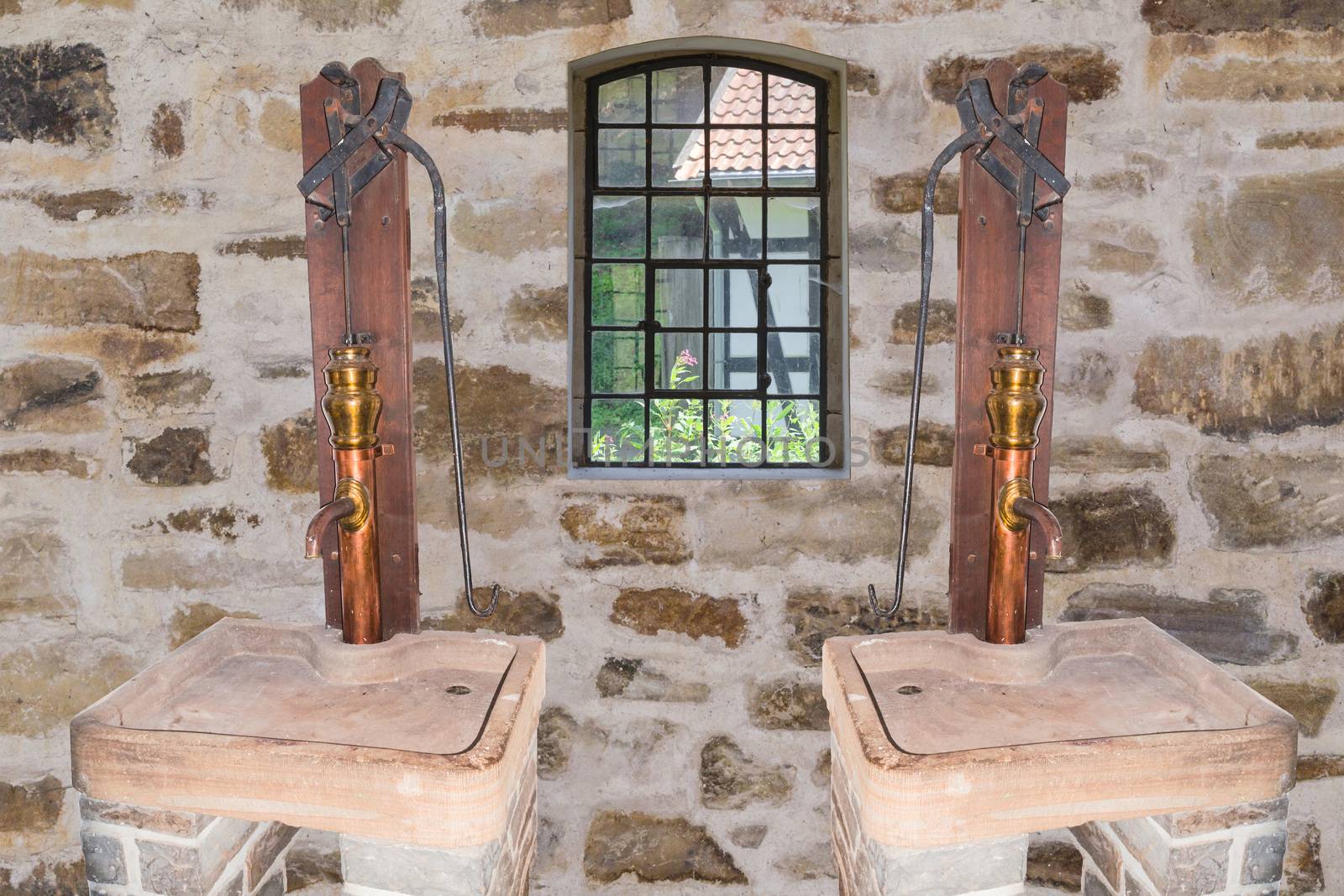 Two antique copper hand pumps in an old building.