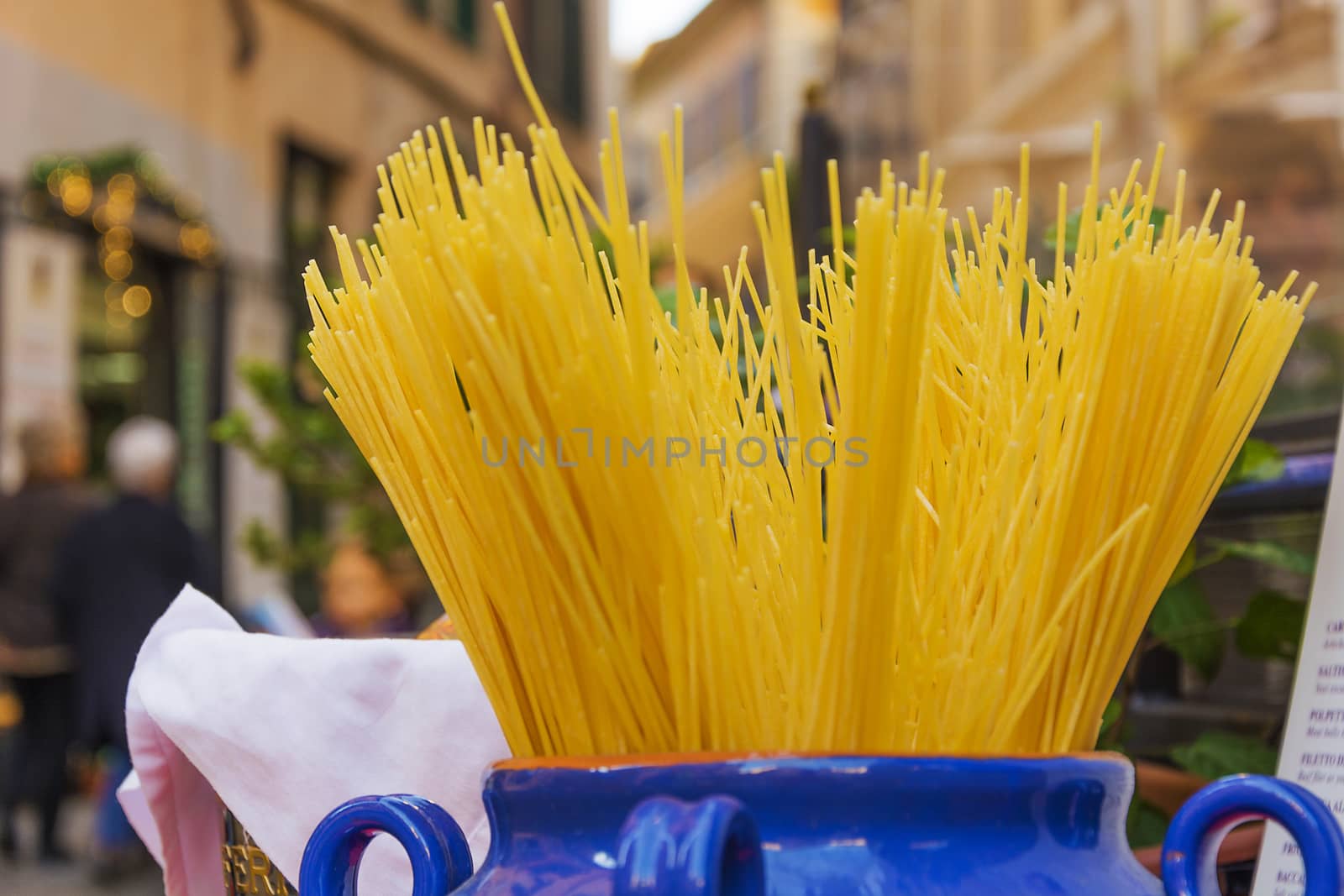 Bundle of uncooked dried Italian spaghetti in a jar in the ancient streets of Rome