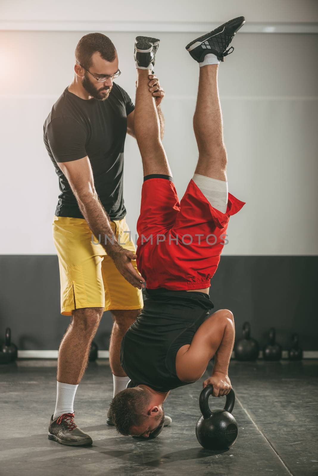 Young man doing crossfit workout with a personal trainer.