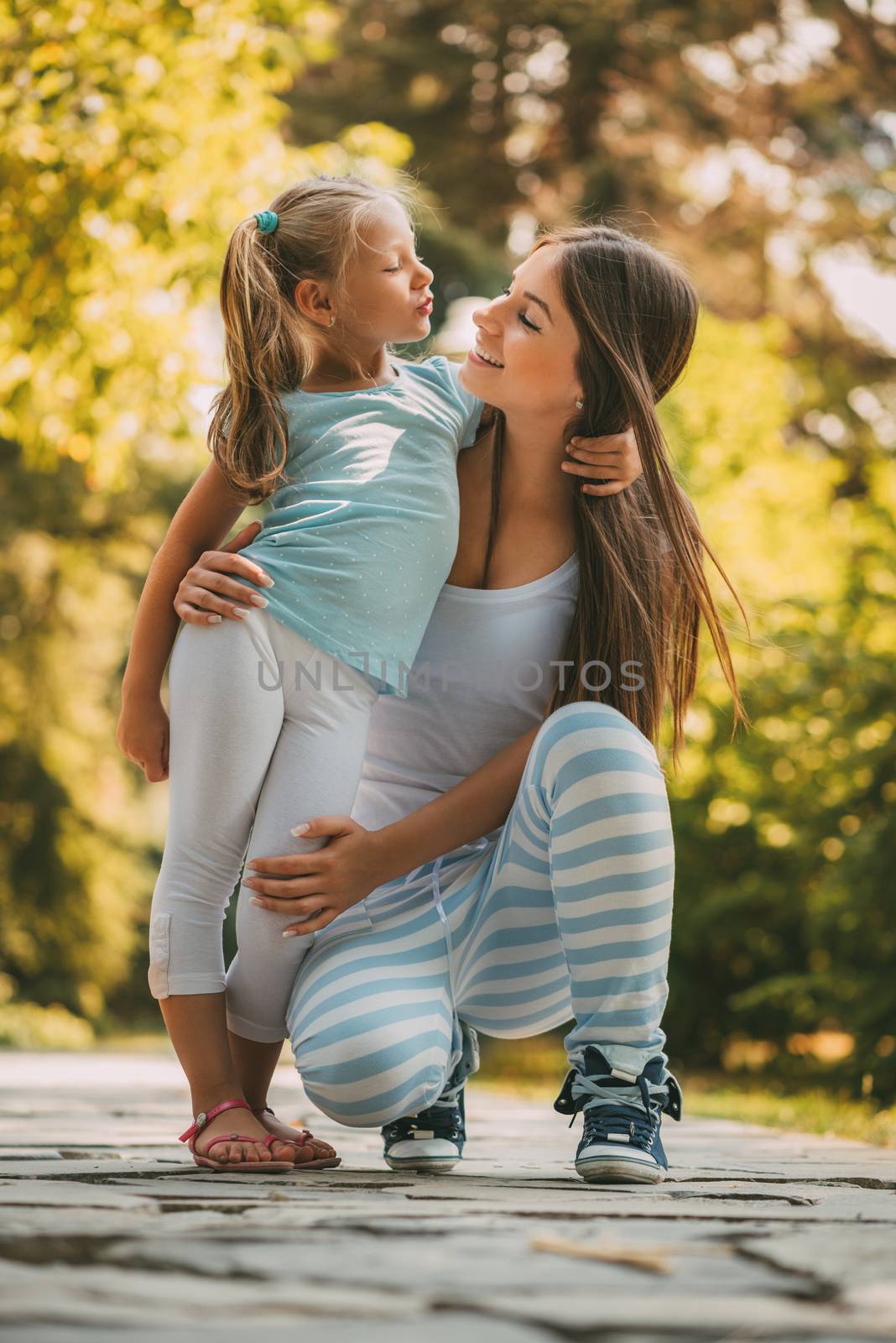 Beautiful mother and daughter posing at the park in spring day.