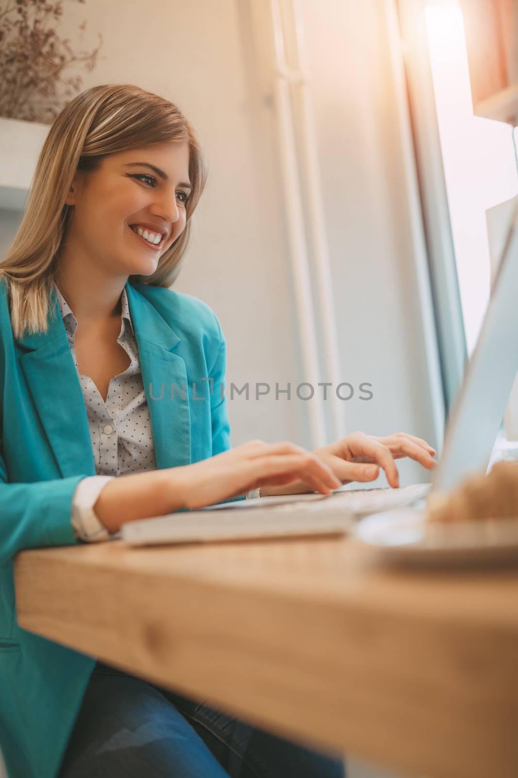 Young smiling businesswoman on a break in a cafe. She is working at laptop. 