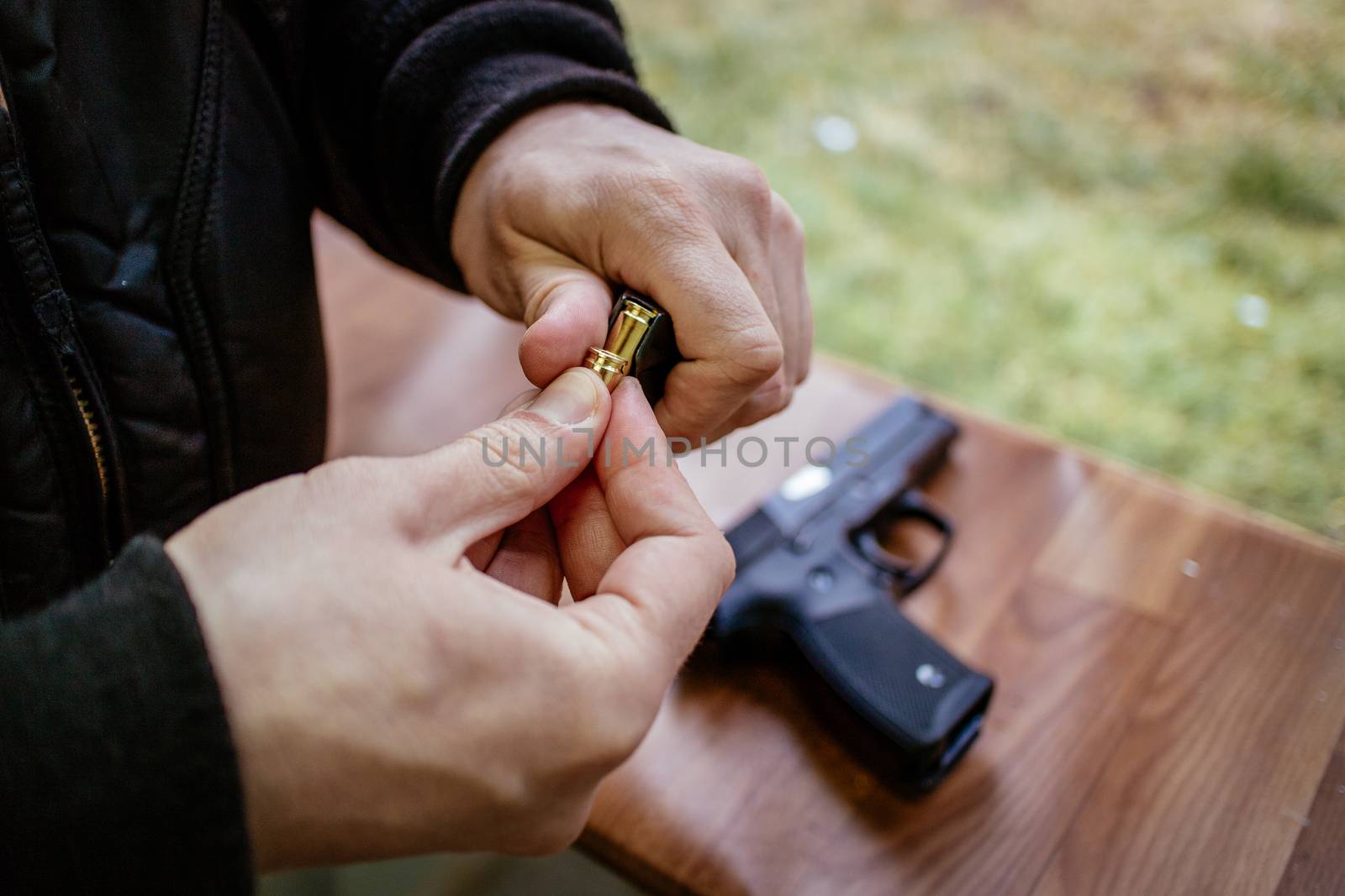 Close-up of a man hands holding and loading 9mm bullets in the pistol at the shooting range.