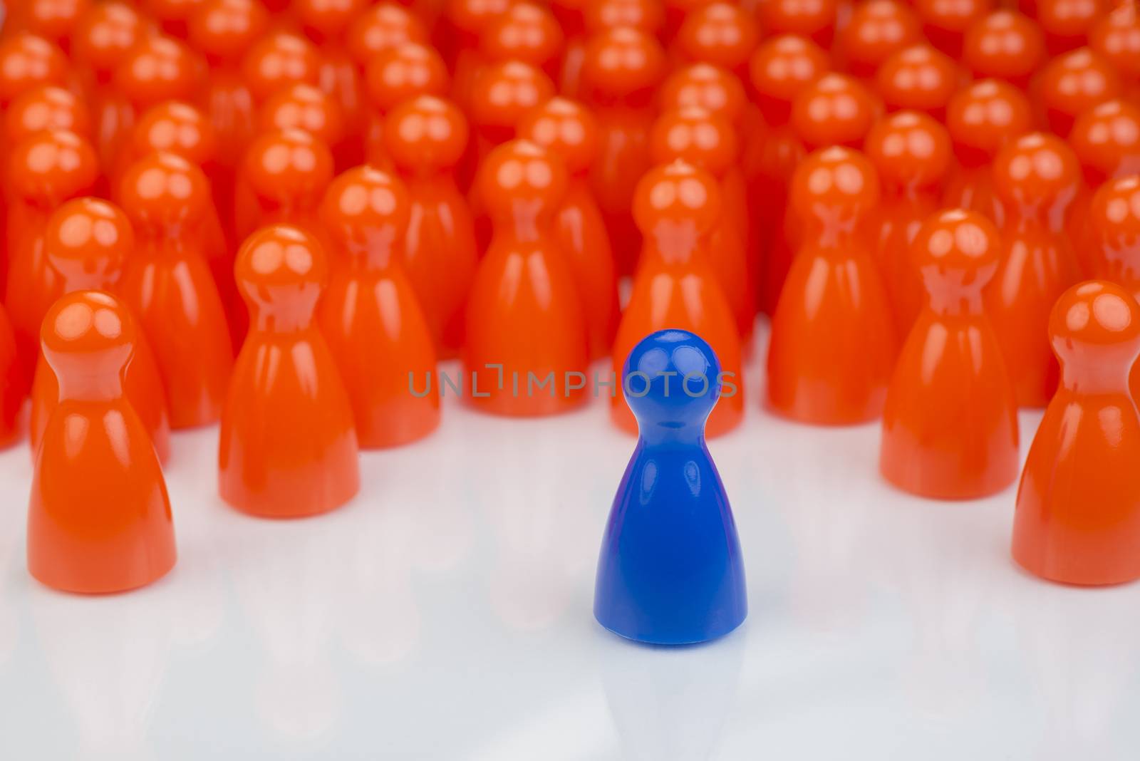 Conceptual orange game pawns and a blue play pawn by Tofotografie