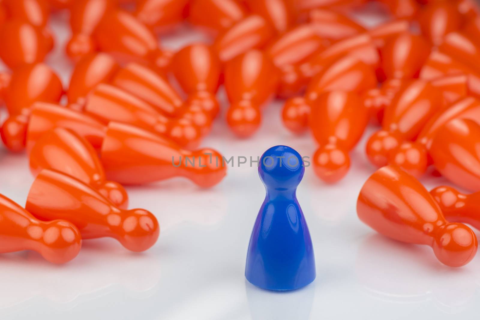 Conceptual orange game pawns and a blue play pawn by Tofotografie