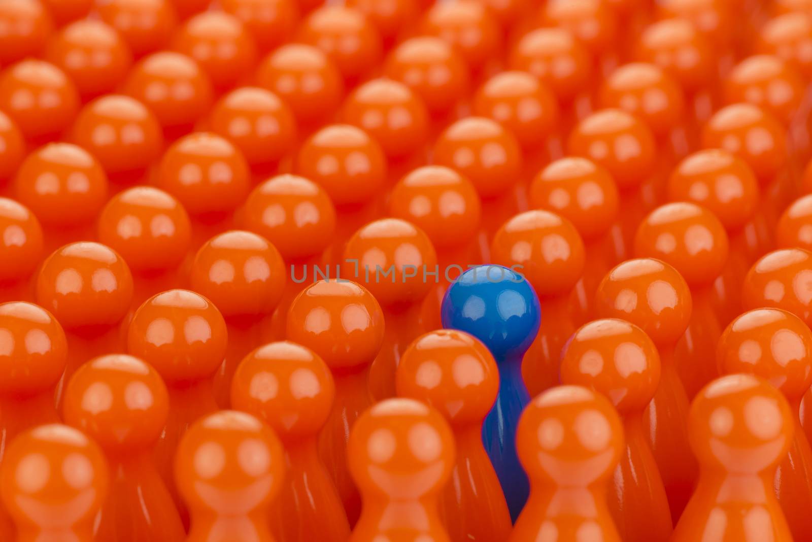 Conceptual orange game pawns and a blue play pawn by Tofotografie